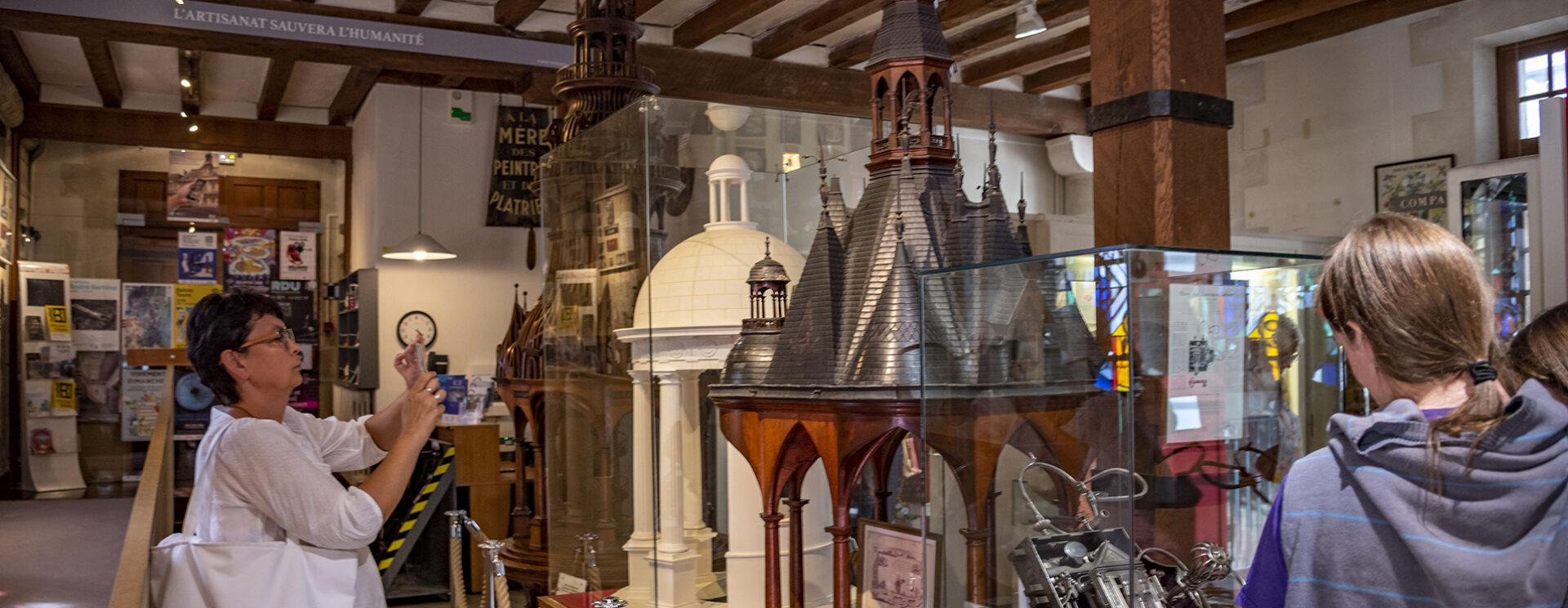 une femme photographie une œuvre au musée du compagnonnage